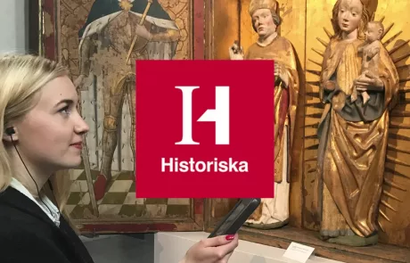 Kvinna med mobil titta på altartavla - Historiska logo finns också